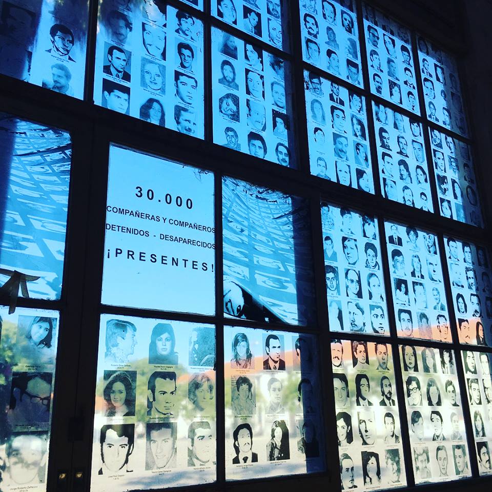 A photo of a window with names and faces of those missing.
