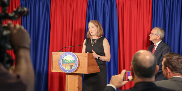 Woman at a podium with blue and red draping behind it
