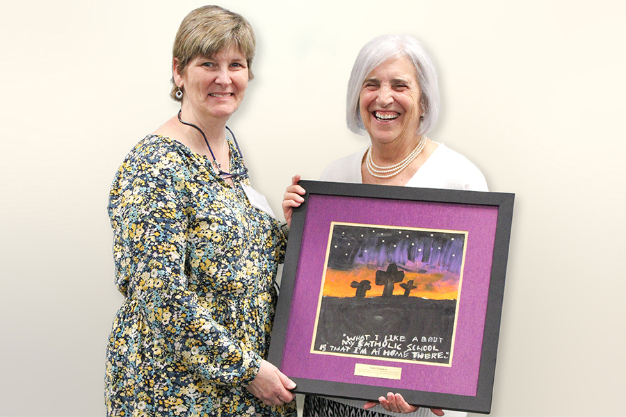 Lumen Fidei winner Linda Dintaman with her nominator, holding a painting of three crosses against a night sky