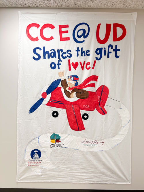 Rudy Flyer in an airplane with the three initiatives of the Center For Catholic Education on a banner behind him