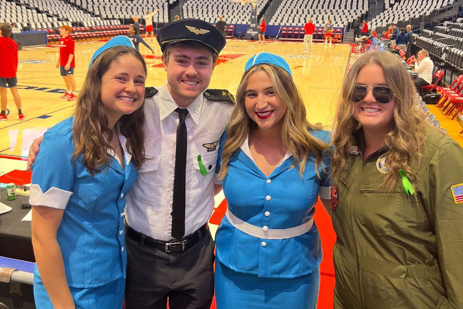 Ryan Peaco in pilot costume posing for a picture with three other students in flight attendant and pilot costumes. 