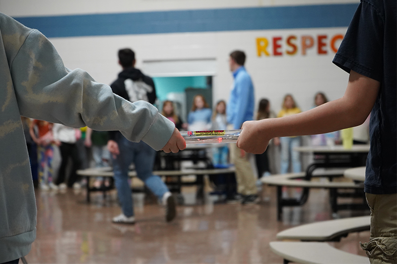 Hands of two young students holding a clear baton