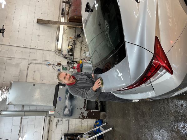 Jerry Zezima standing in a garage, polishing a silver sedan.