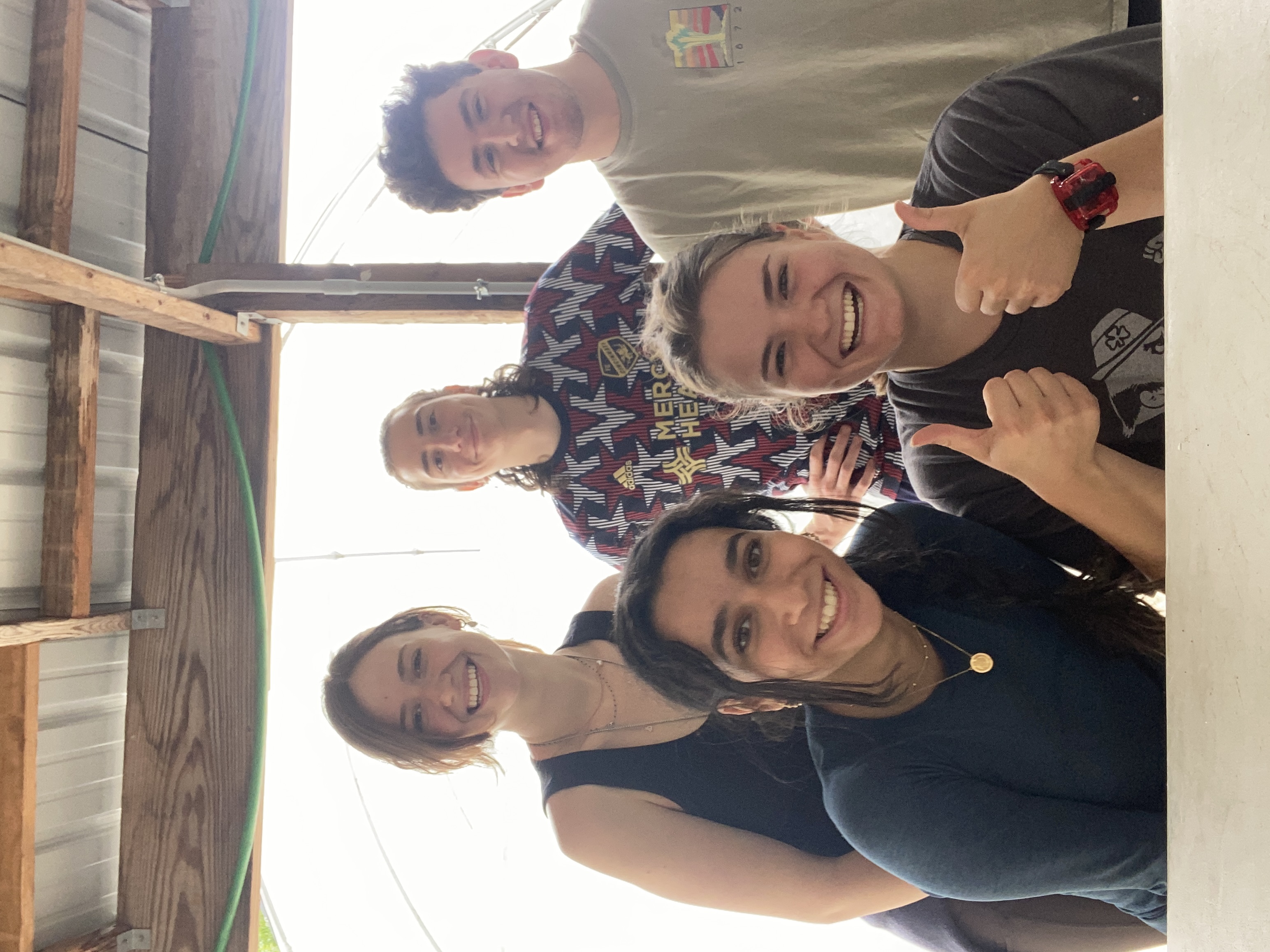 Group of five students smiling while volunteering at a local farm. 