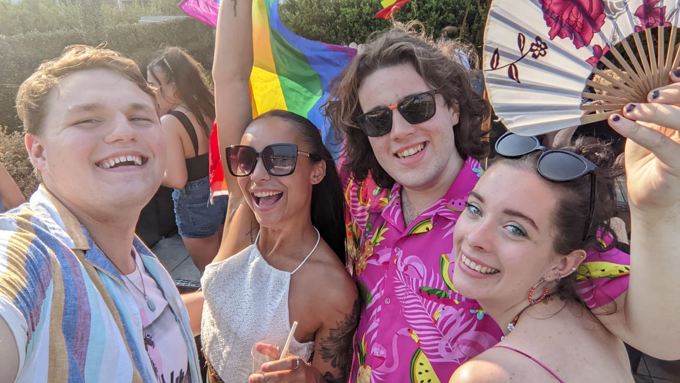 Selfie with four students holding a rainbow flag. 