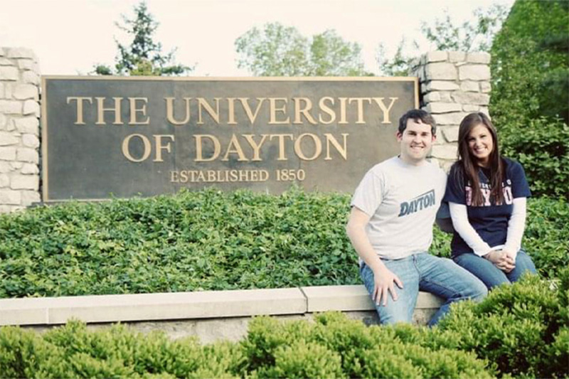 The Plassenthals, in front of the University of Dayton sign