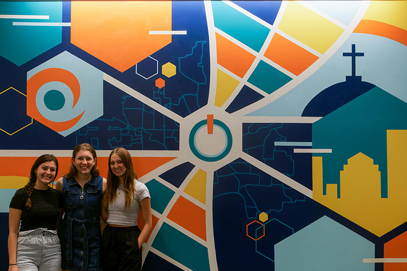 Gracie King, Claire Pawlecki and Mira Holifield standing in front of their finished mural at The Hub Powered by PNC Bank.