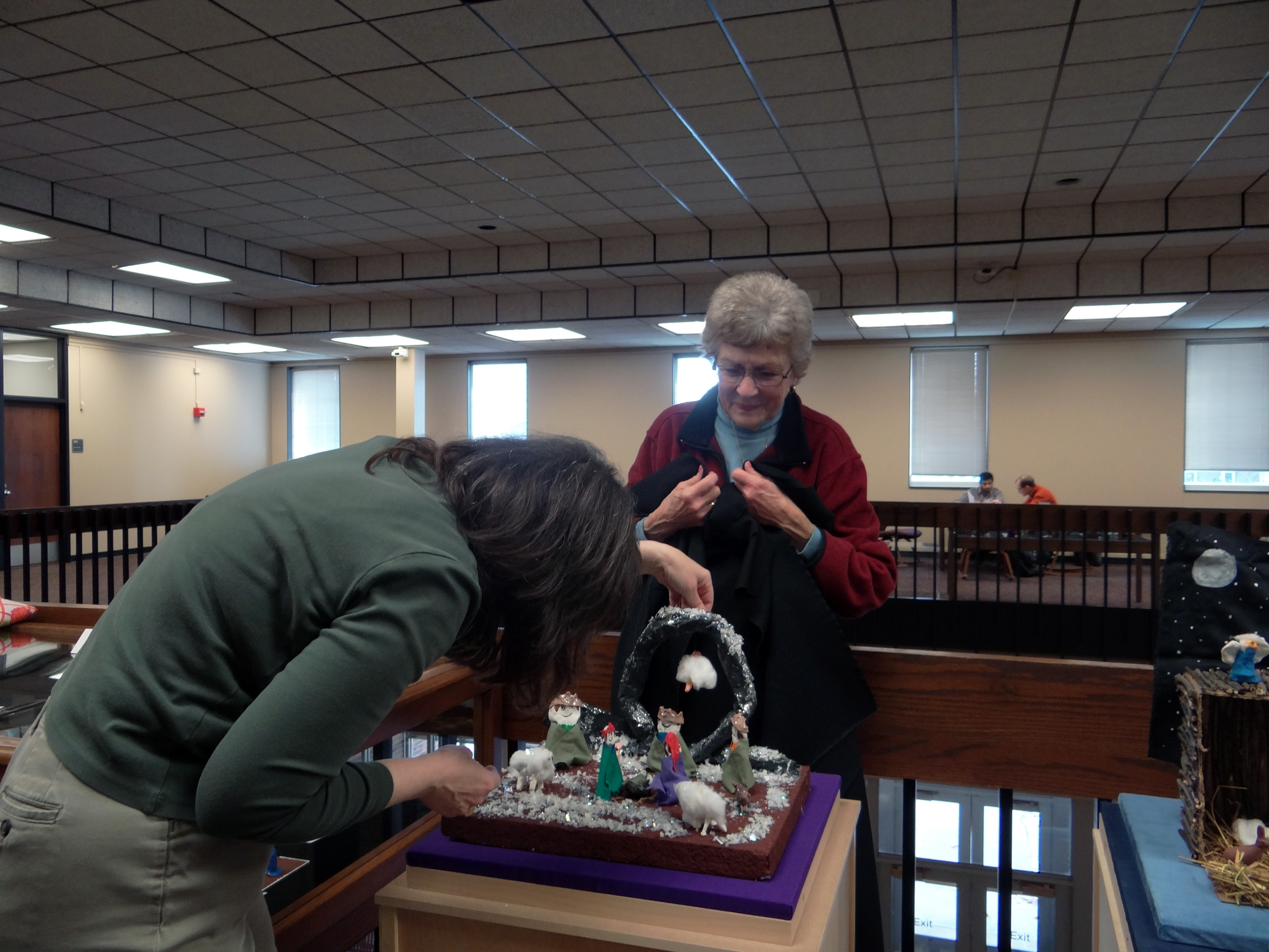 Volunteers Anne Malone and Ginny Saxton set up a nativity set for an At the Manger exhibit.