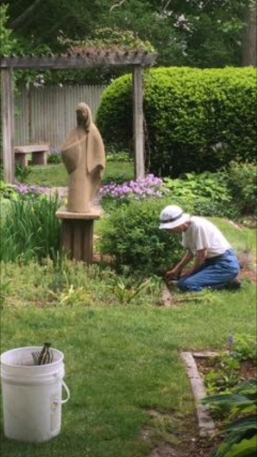 Cynthia Rose, caretaker of the Mary garden at Woods Hole, gardening near the iconic statue of Mary.