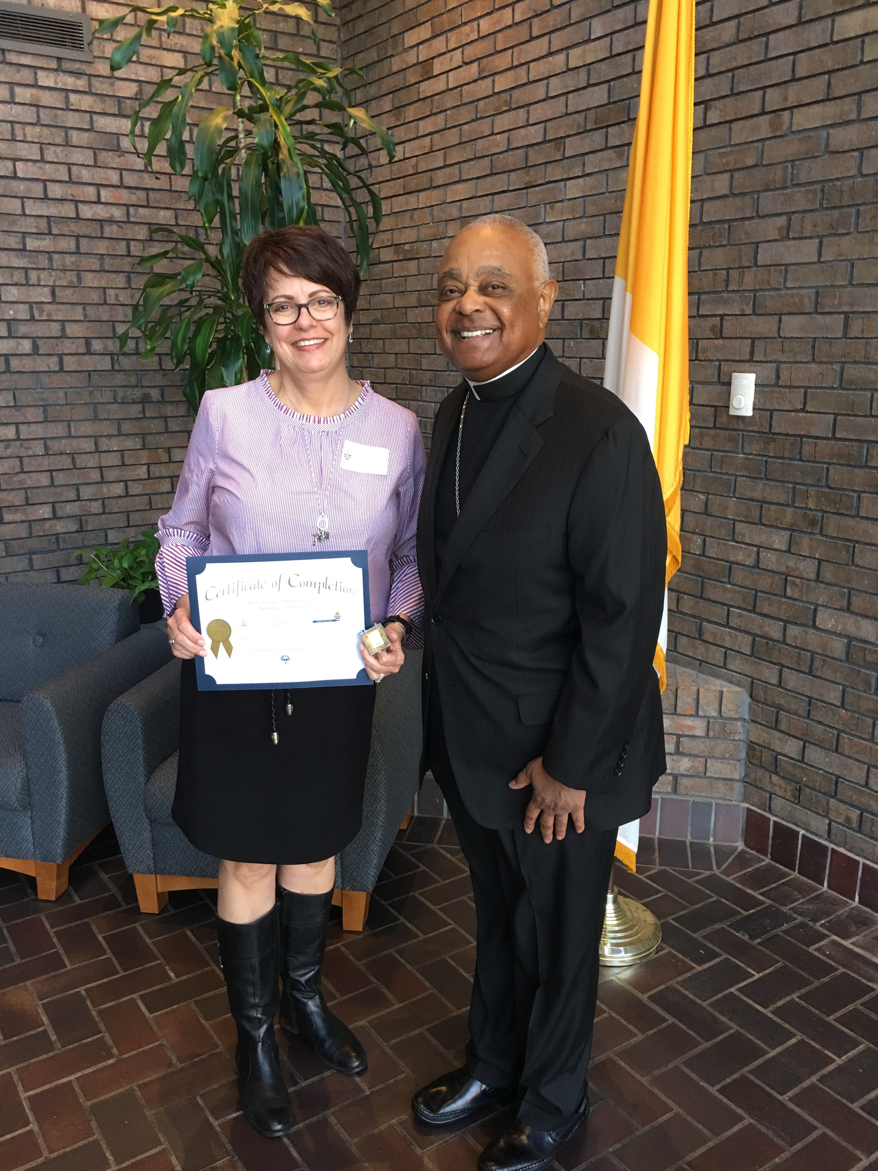 An adult e-learner from Georgia shows off her certificate of completion ( with the Archbishop of Atlanta )