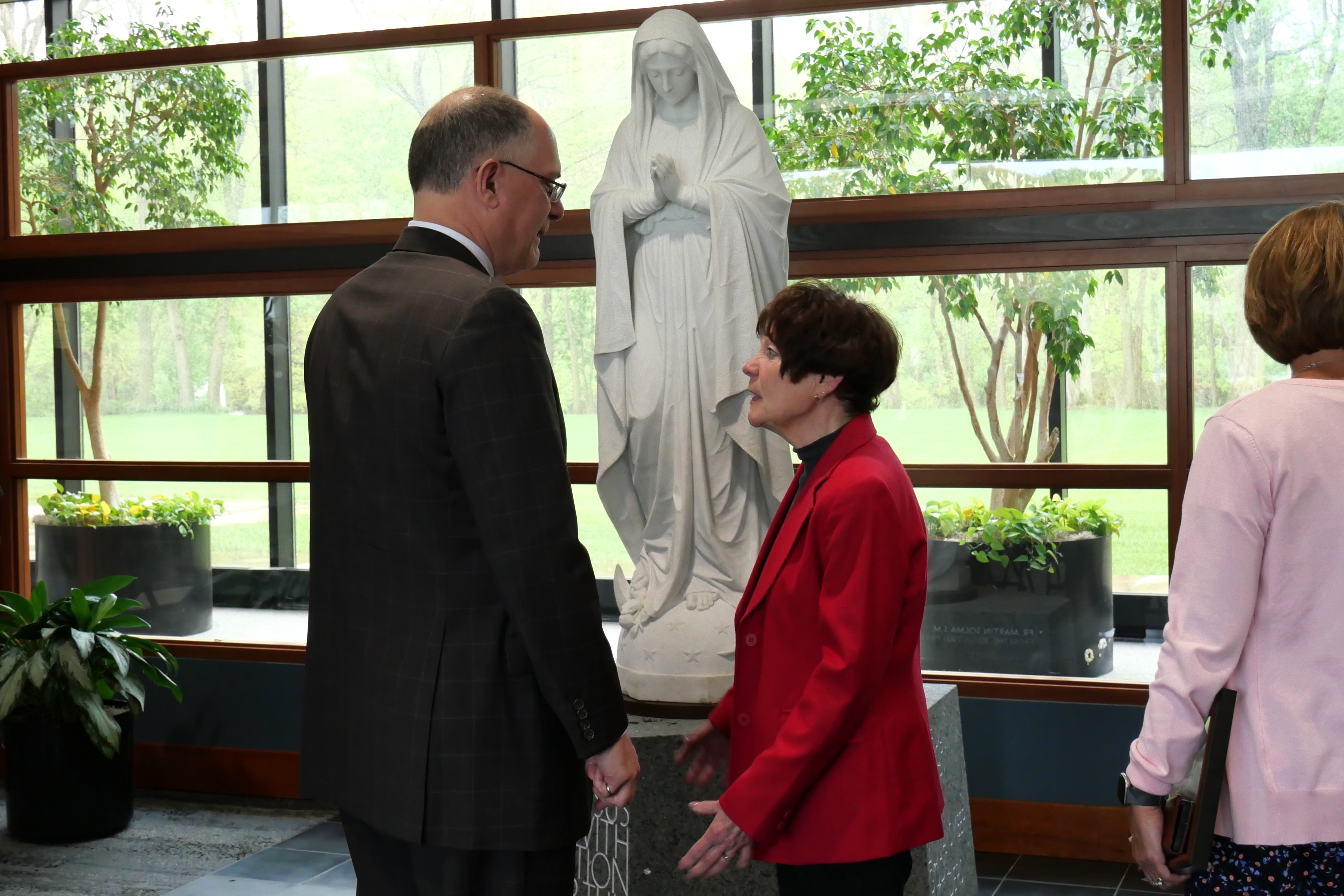 President Eric Spina and Patti Procuniar talk in front of statue