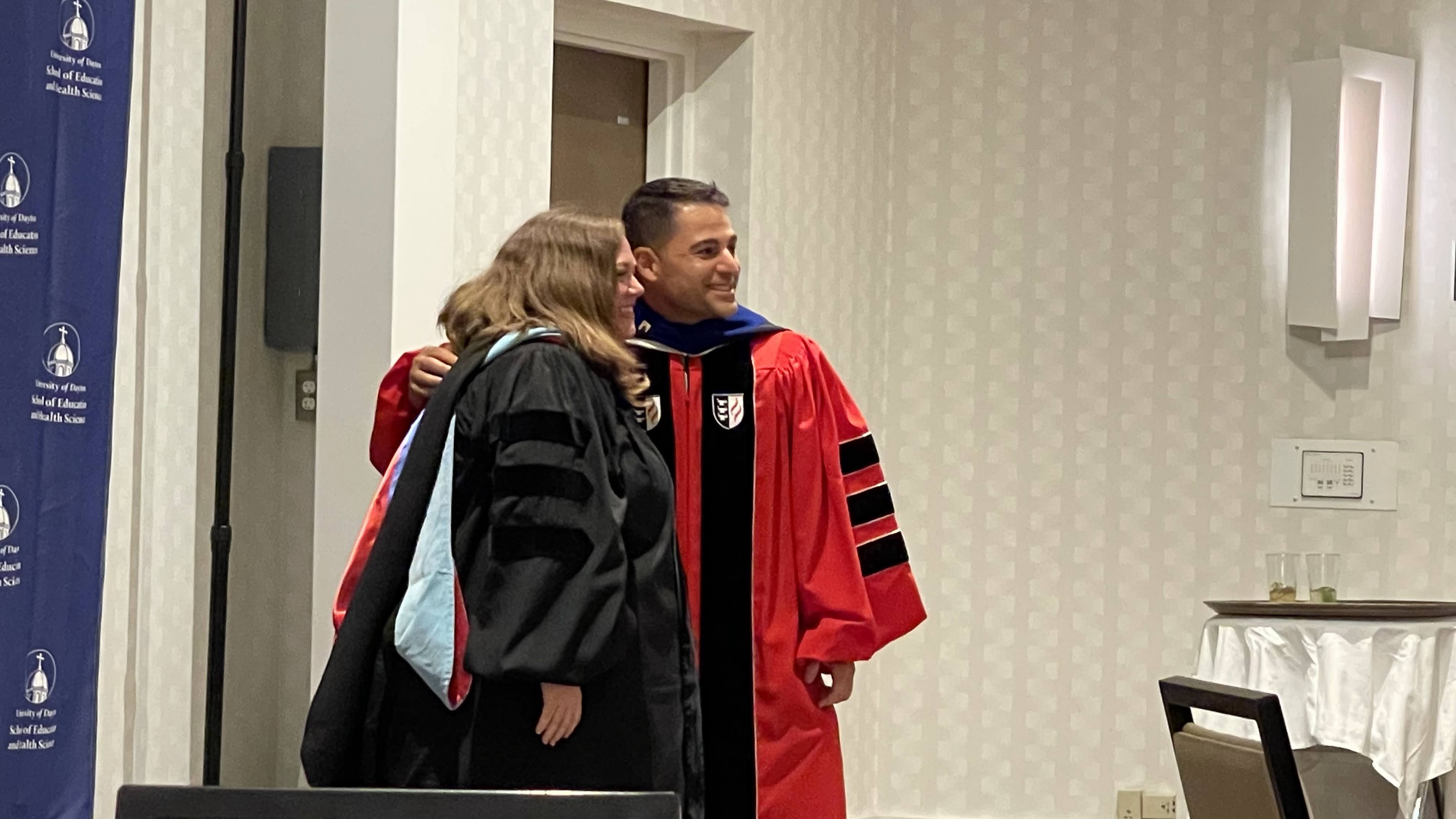 Dr. Witenstein takes a photo with a student after the hooding event.