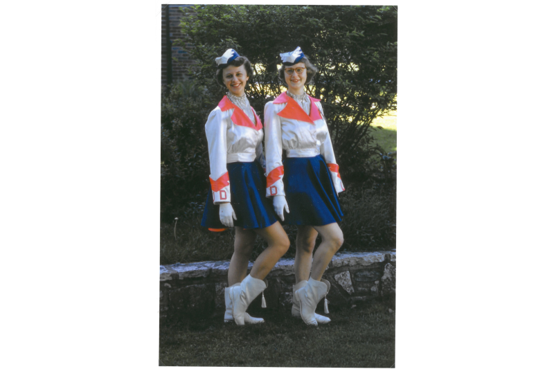 two Flyerette cheerleaders standing in front of some trees