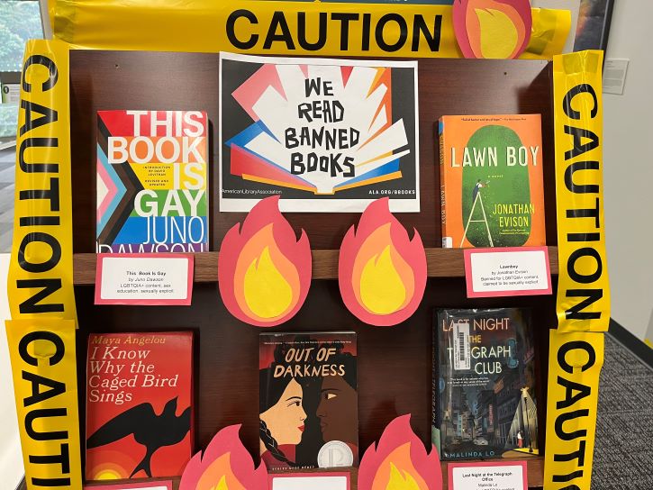 book display of banned books titles with caution tape and paper flames 