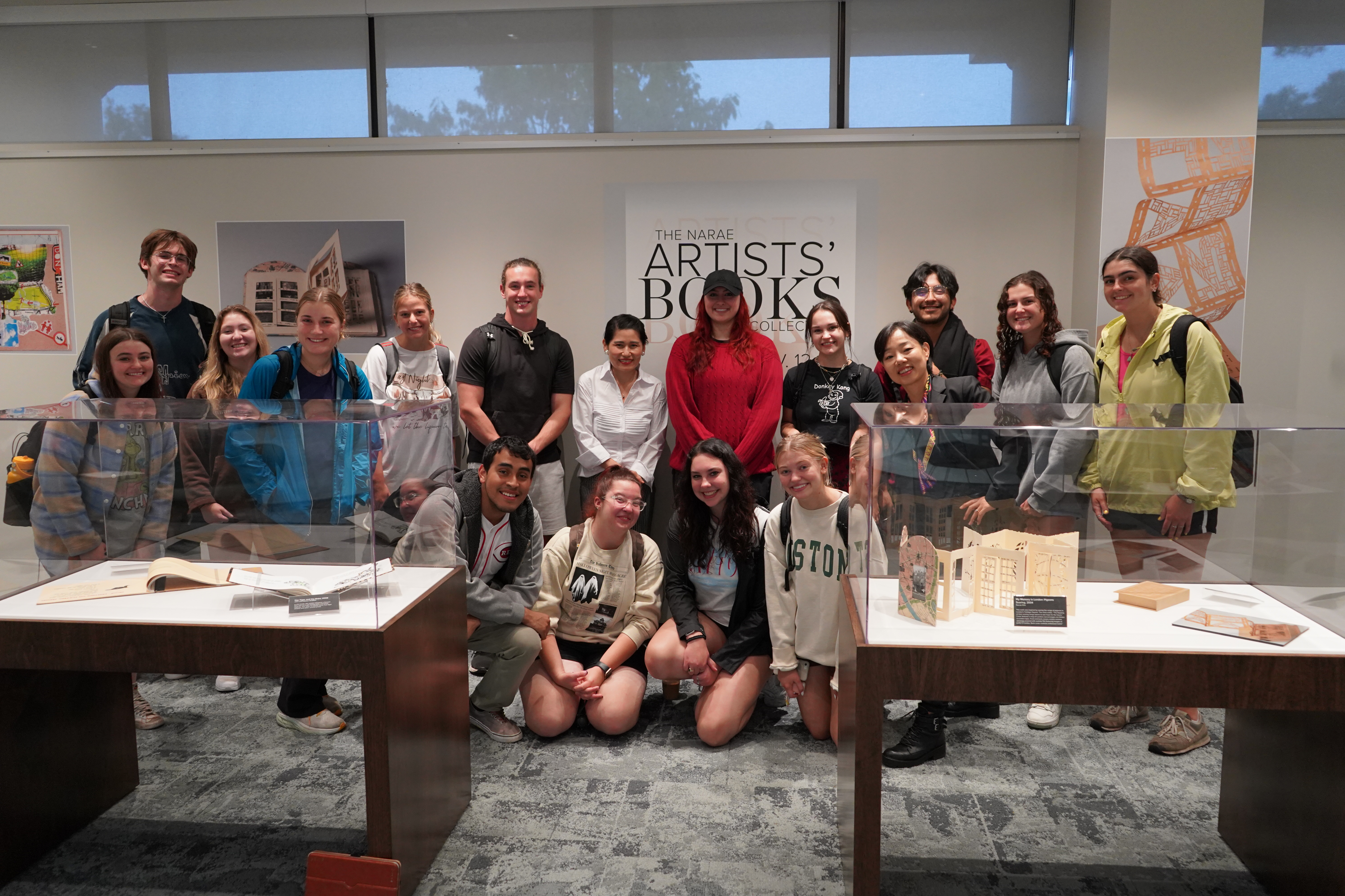 students, artists and faculty members pose in an exhibit of artists books