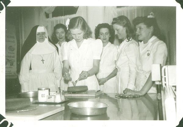 Five dietetics students and a teacher work with a cake during a 1945 evening class.