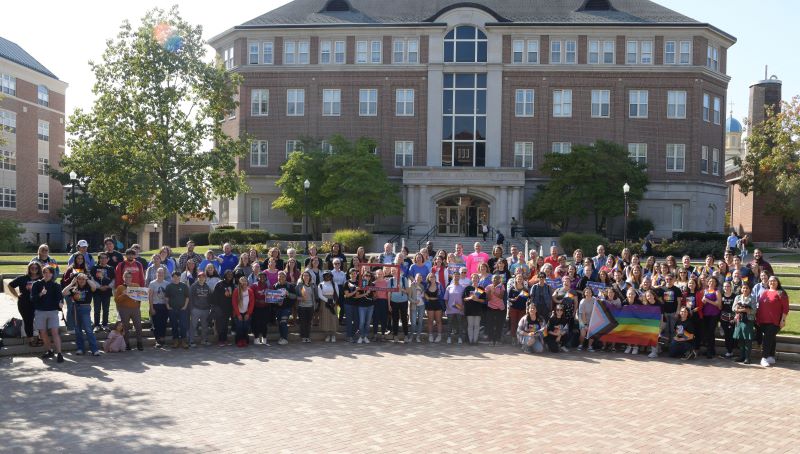 a group of UD, faculty and staff pose in humanities plaza for national coming out day