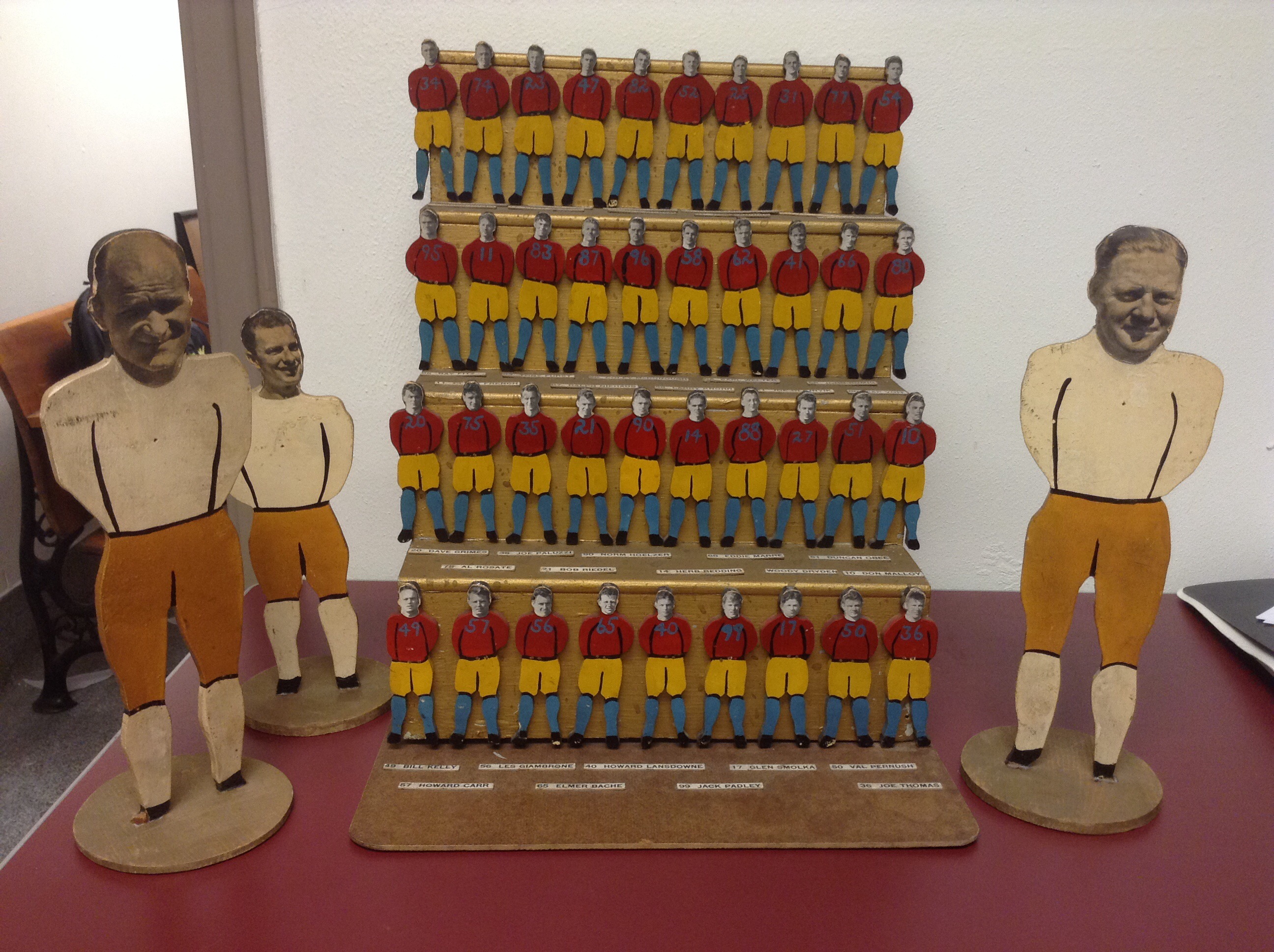 Football team sculpture with faces of athletes pasted onto wooden figures