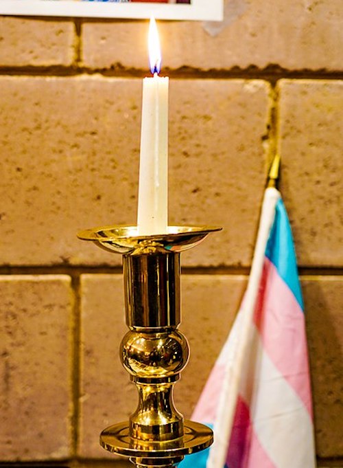 Candle and transgender pride flag in memory of victims of transgender violence