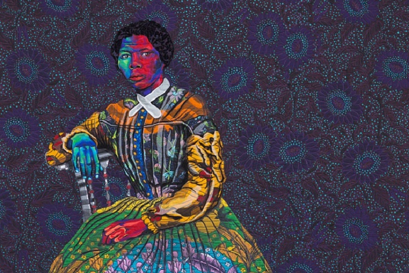 A quilted and appliquéd textile portrait of Harriet Tubman by Bisa Butler, based on the carte-de-visite photograph portrait of Tubman by Benjamin F. Powelson (NMAAHC 2017.30.47). The quilt depicts Tubman, in multiple bright-colored fabrics, seated against a dark floral background. Tubman gazes directly at the viewer, her proper right arm on the back of the chair and her proper left hand in her lap. Her face and hands are shown in contrasting shades of blue and purple with rich reds, symbolizing Tubman’s coolness, calmness, and strength as well as her power and force. Her hair is made of a deep velvet cloth, soft and opulent to mimic the soft texture of some African American hair.