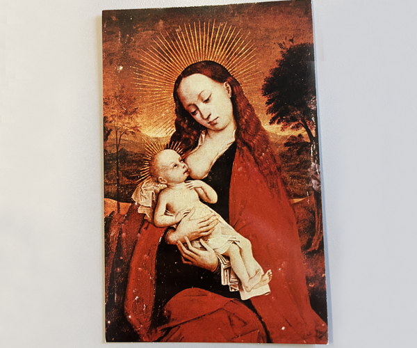 Vibrant reds, oranges and black tones make up this artwork of the Madonna, with long wavy red hair, sitting and propping up the Infant Jesus while he nurses. A fiery orange sky and landscape with trees make up the background.