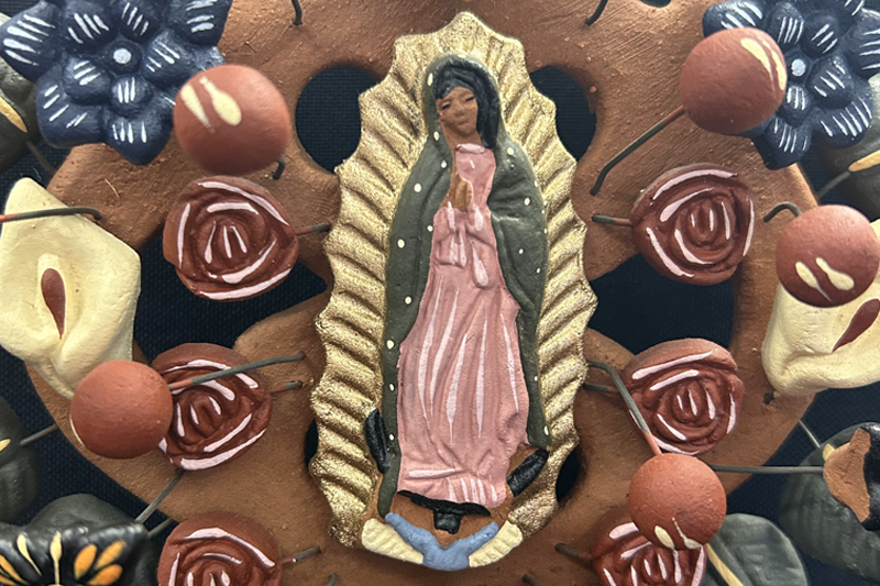 Our Lady of Guadalupe depicted among the clay flowers and design elements in a tree of life sculpture.