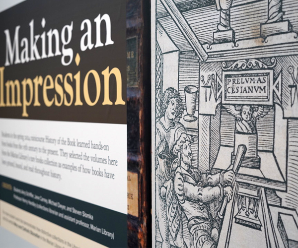 The banner above the case for the mini-course’s display case, featuring a 16th-century woodcut used by Jodocus Badius Ascensius, shows a wooden printing press in a printshop.