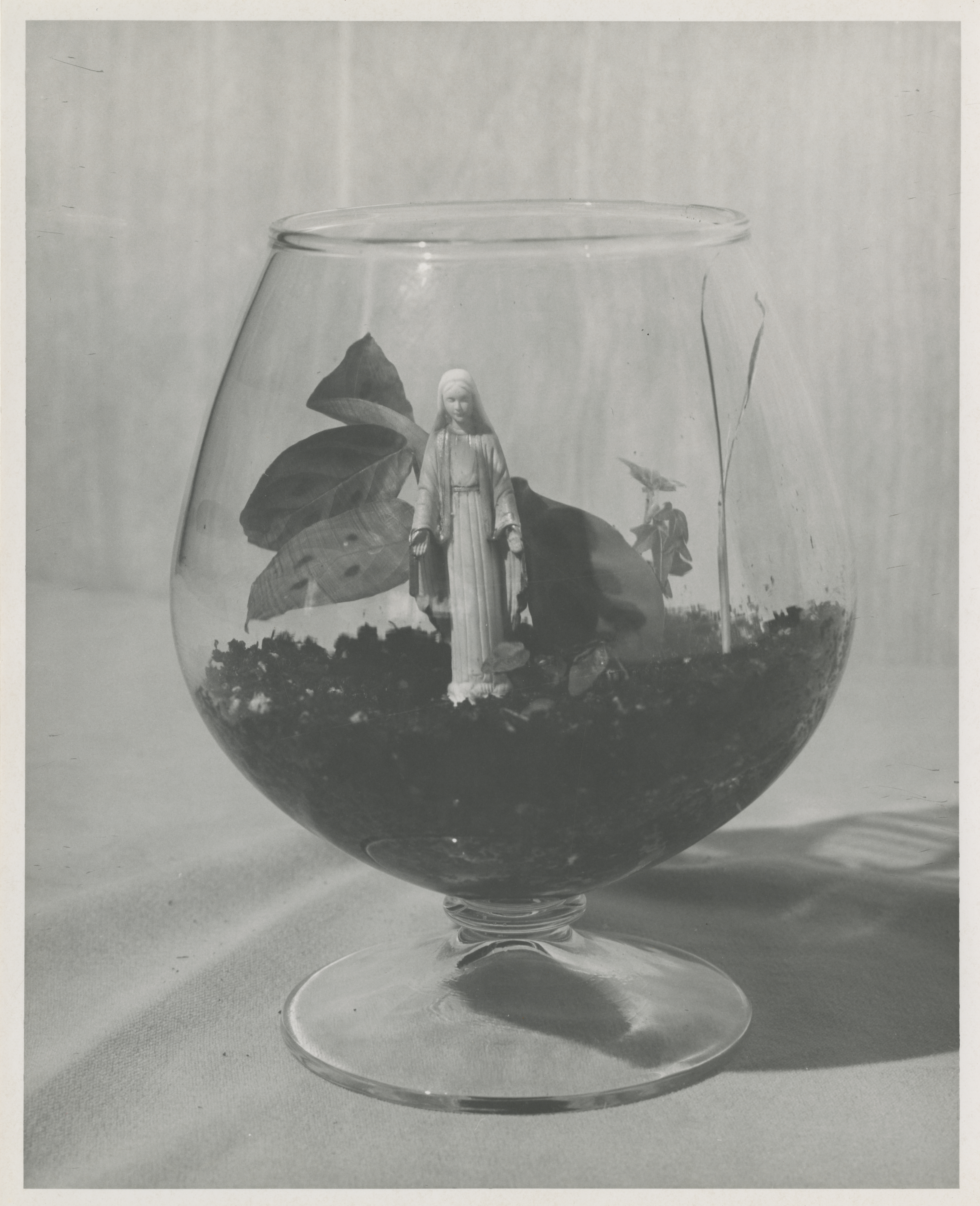 Black and white photo of a solid white Madonna statue in a brandy snifter