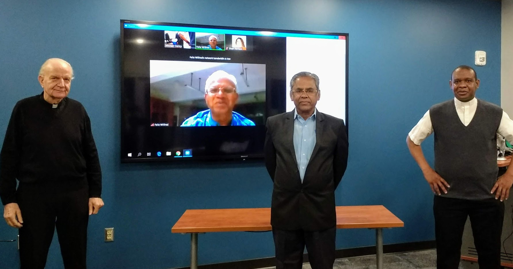 The socially distanced dissertation defense of Father Rayar “R.K.” Kulandaisamy, from left: Father Johann Roten, S.M., director; Father Felix Wilfred, reader, shown via video conference; Kulandaisamy; and Father Sebastien Abalodo, S.M., reader.
