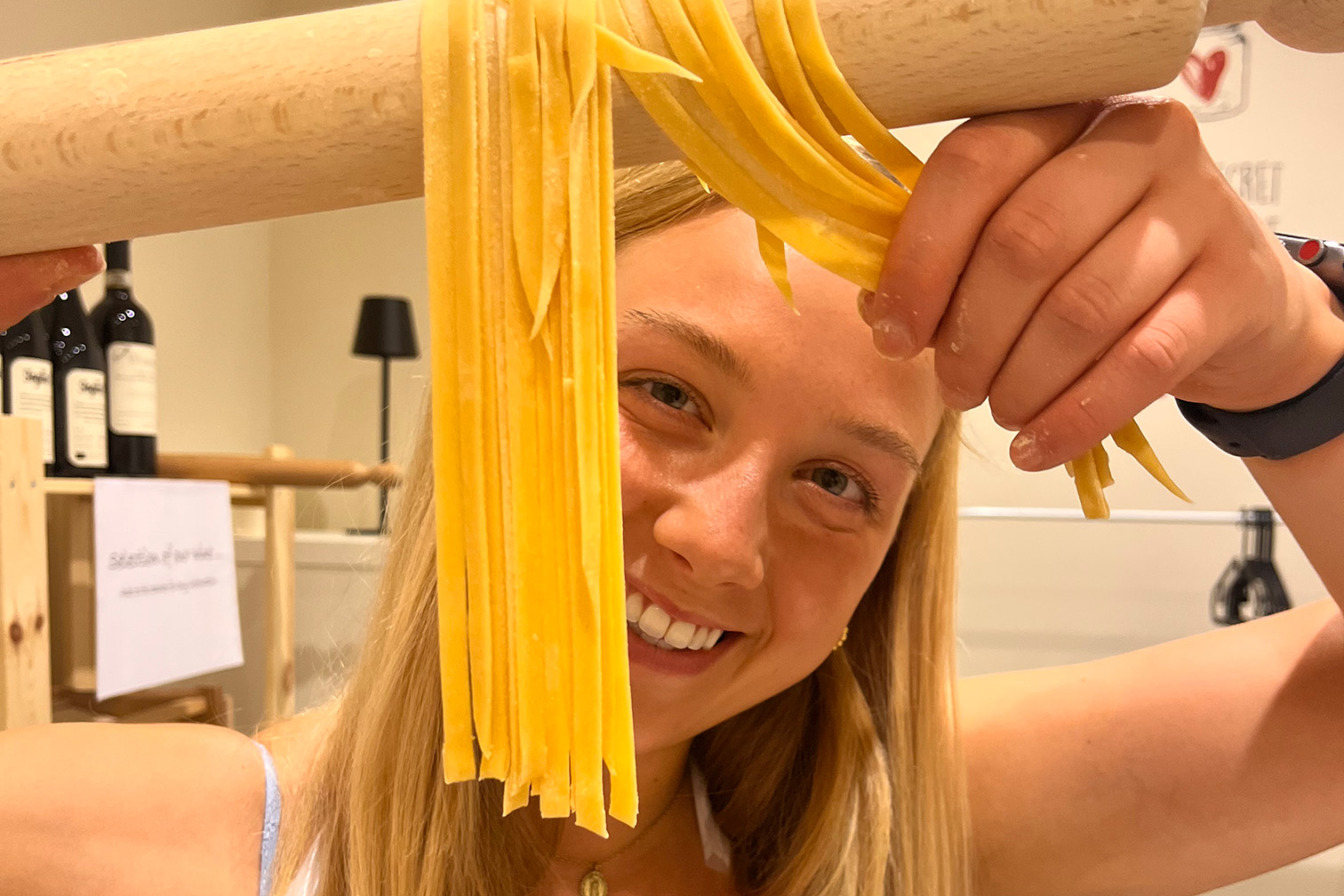 A girl looking through strands of pasta.