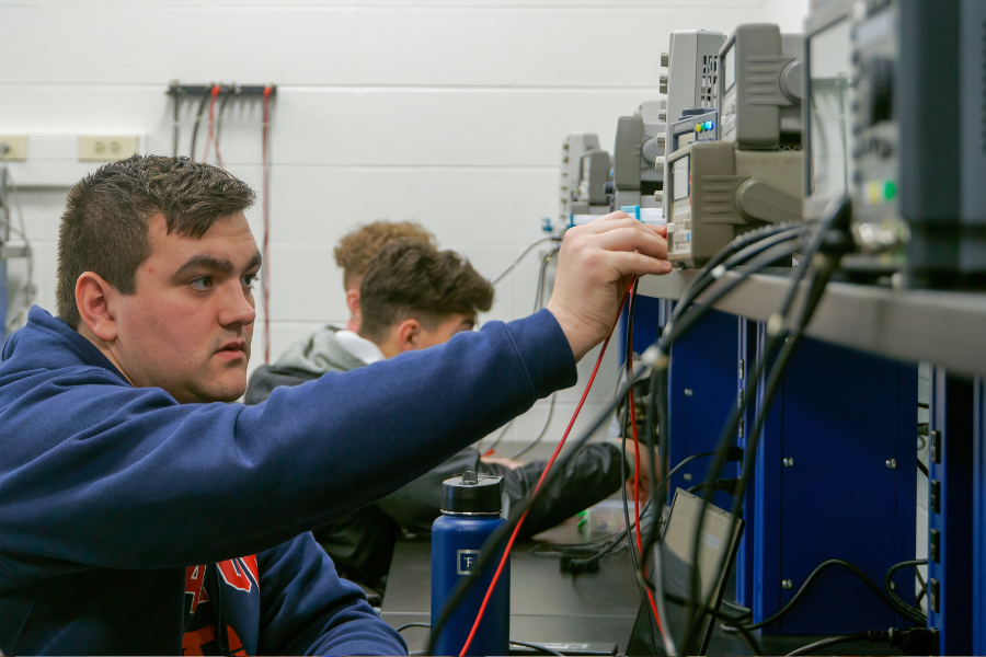 Student working with electrical and computer lab equipment.