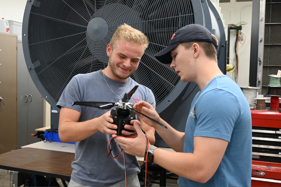 Two students looking at a small plane propeller. 