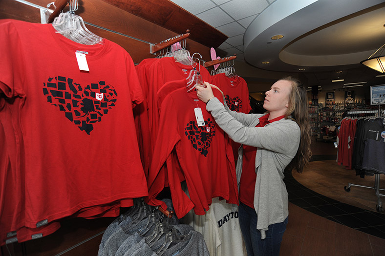 A student arranges a display of T-shirts in the bookstore