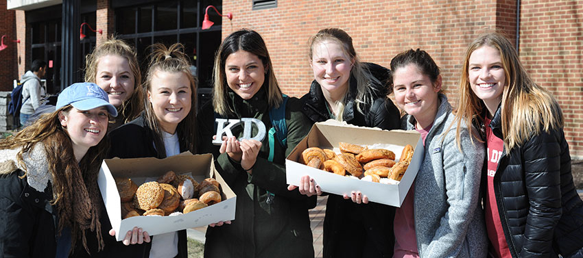 Members of Kappa Delta providing doughnuts to passers-by.