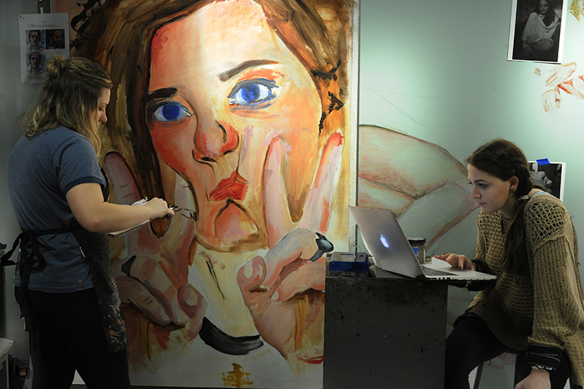 art students work on larger than life self-portraits.