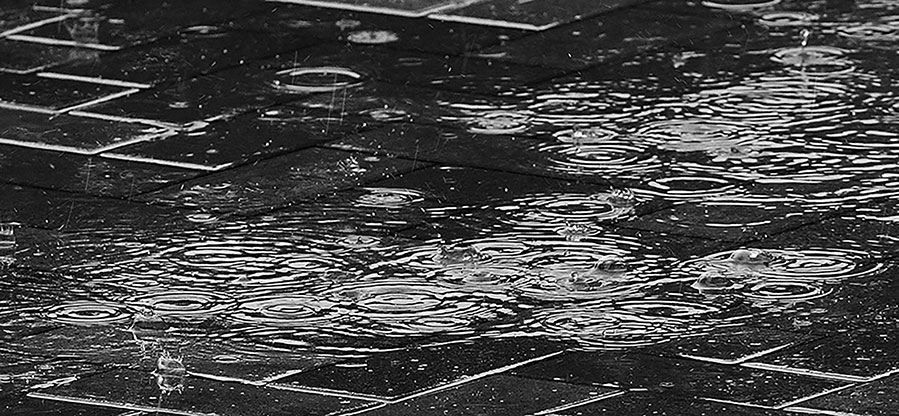 black and white photo of rain on concrete