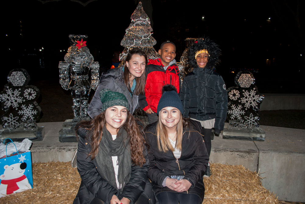 A group of students and children pose in front of ice sculptures for a group photo.