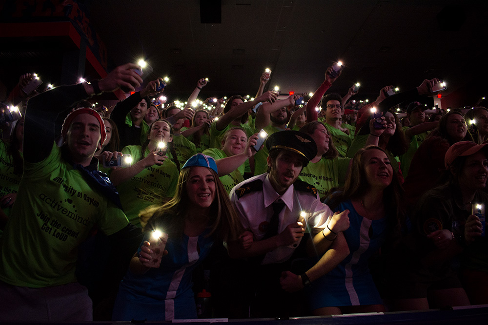 students hold lights at a basketball game
