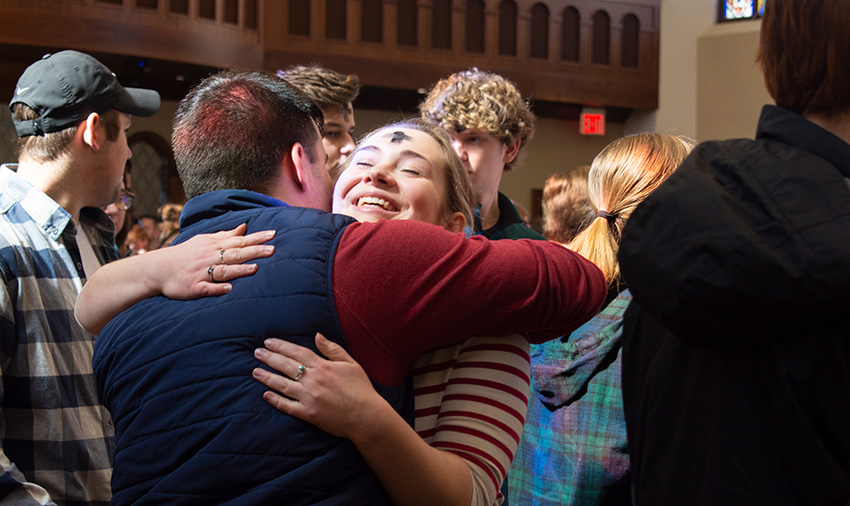 student embrace to share the sign of peace during Ash Wednesday Mass