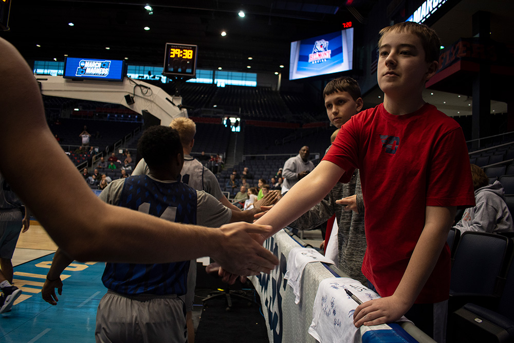 A kid from Dayton High fives a basketball player