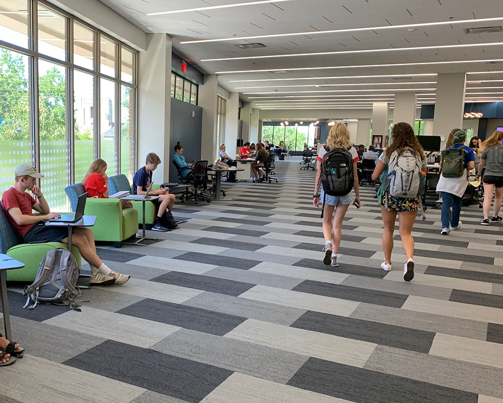 students study in a renovated Roesch Library with open spaces and lots of windows and comfy chairs
