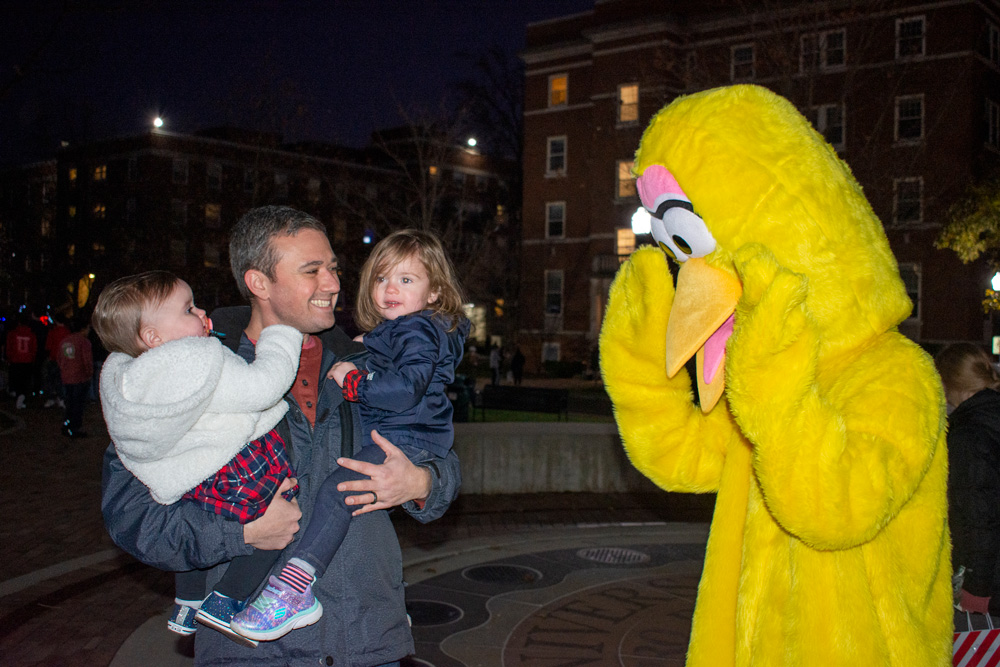 Father holds two children to meet a life-sized Big Bird