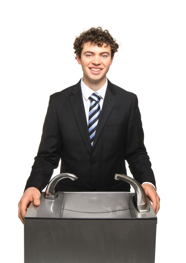 Man in a suit stands at a sink