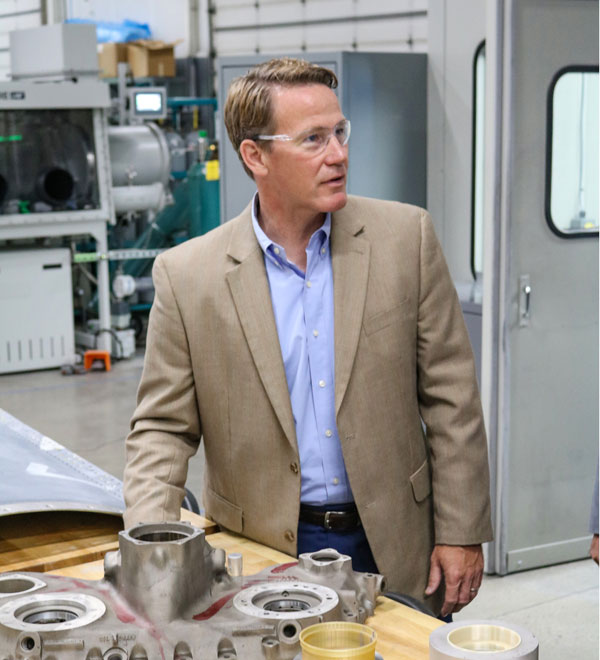 Jon Husted stands in front of research equipment