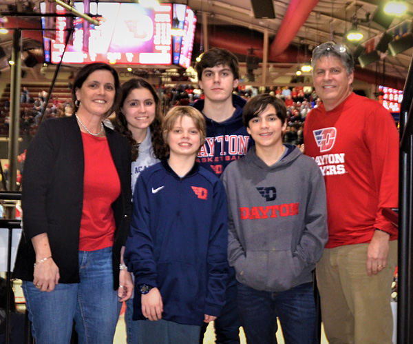 Family with mom, dad and four kids stands in front of a court before a basketball game