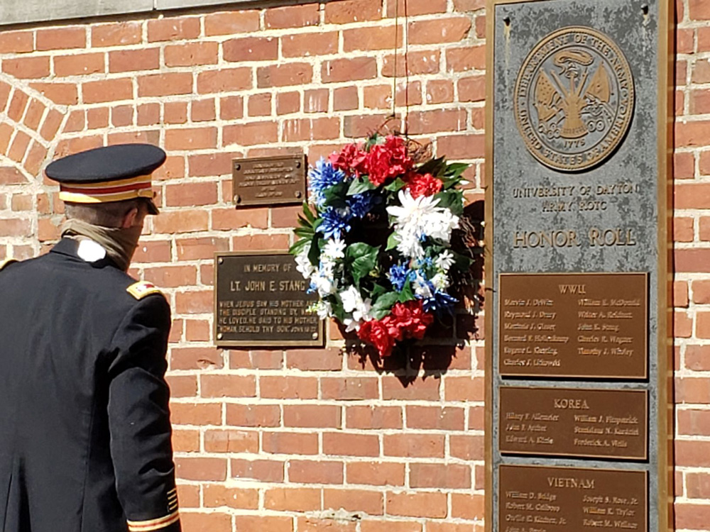Red, white and blue flowered wreath hangs on a brick wall