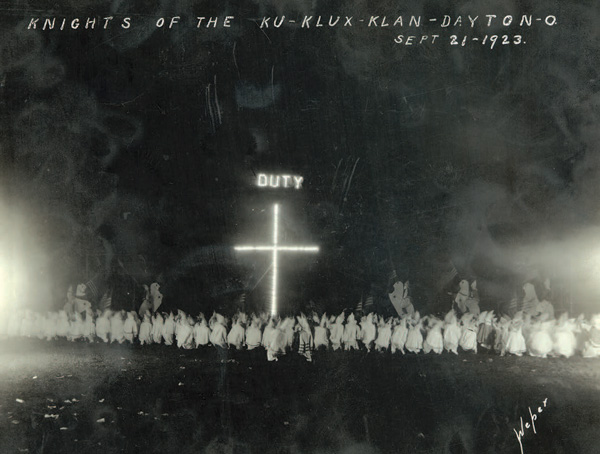 Robed members of the Ku Klux Klan in front of an illuminated cross