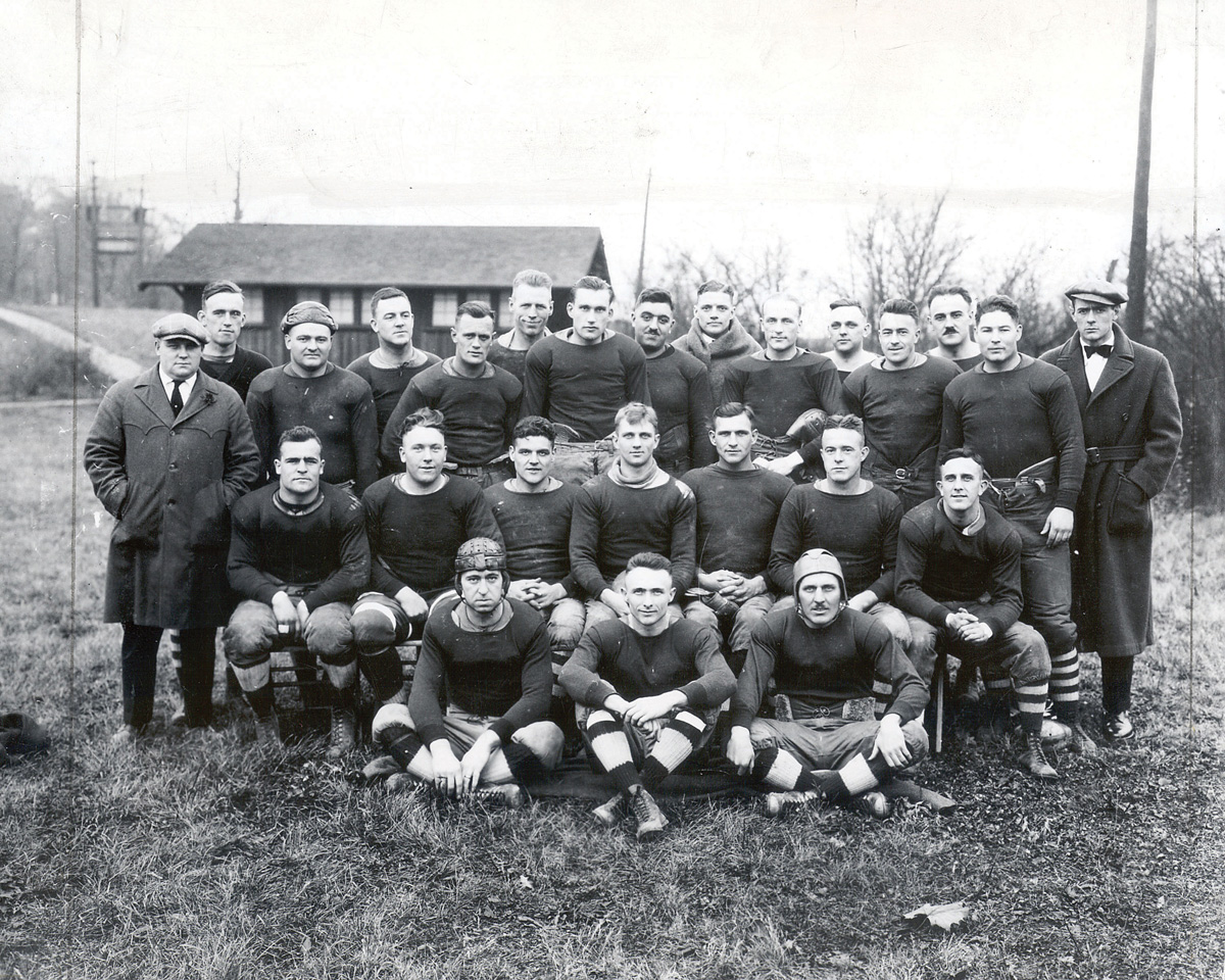 Three rows of football players with coaches on either side, black and white