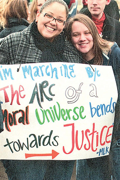 Two students hold the sign "I'm marching because the arc of a moral universe bends towards justice."