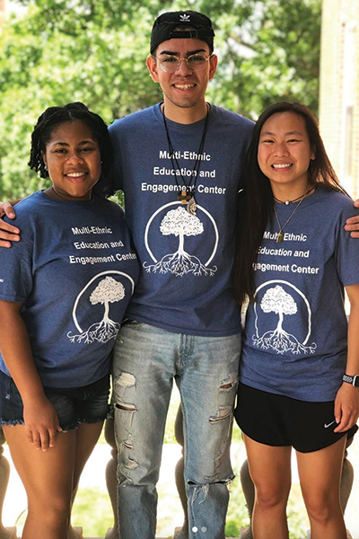 Three students stand together wearing MEC shirts. 
